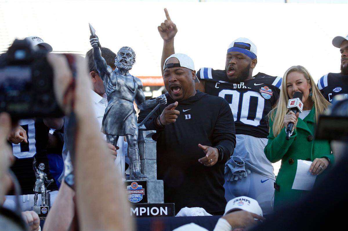 Dec 23, 2023; Birmingham, AL, USA; Duke Blue Devils interim head coach Trooper Taylor and all-ACC defensive tackle DeWayne Carter react as they are presented with the Birmingham Bowl trophy after defeating the Troy Trojans at Protective Stadium.