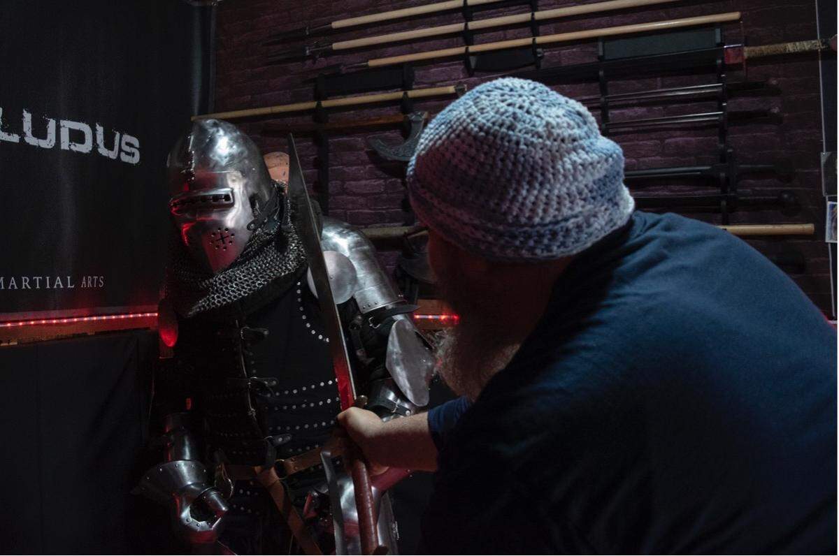 Dire Drakes leader Jeff Barnes slams Jarred Bender with a dulled axe at a Dire Drakes practice. The team’s members, outfitted in 80 pounds of steel armor, shields and dulled axes and swords, compete in an up-and-coming worldwide sport that combines extreme athleticism and the history of 14th- and 16th-century combat styles.