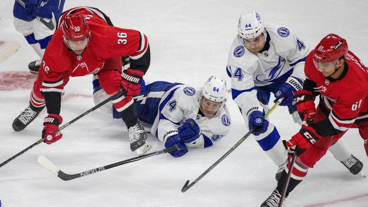 Carolina Hurricanes’ Ryan Suzuki (61) controls the puck in front of Tampa Bay’s Jan Rutta (44) and Charles Hudon (54) during the first period of their NHL exhibition game on Tuesday, September 28, 2021 at PNC Arena in Raleigh, N.C.