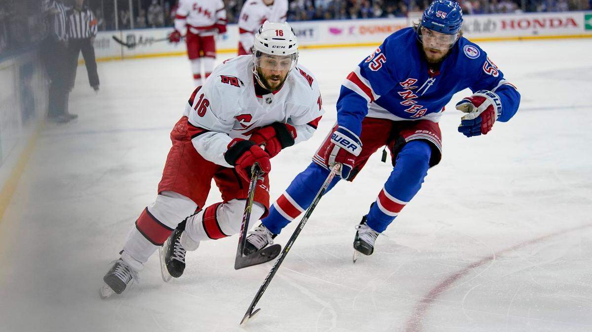 Carolina Hurricanes center Vincent Trocheck (16) and New York Rangers defenseman Ryan Lindgren (55) chase the puck in the first period of Game 4 of an NHL hockey Stanley Cup second-round playoff series, Tuesday, May 24, 2022, in New York. (AP Photo/John Minchillo)