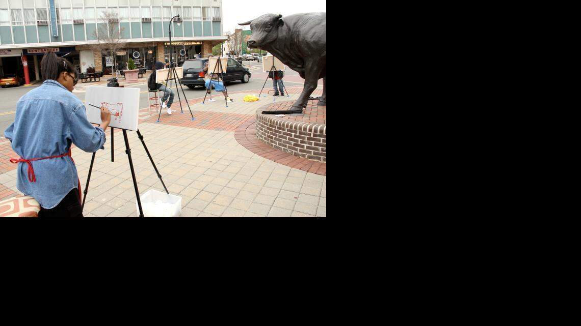 Kaitlin Kimbro paints the bronze bull in downtown during a Durham Art Walk. 
