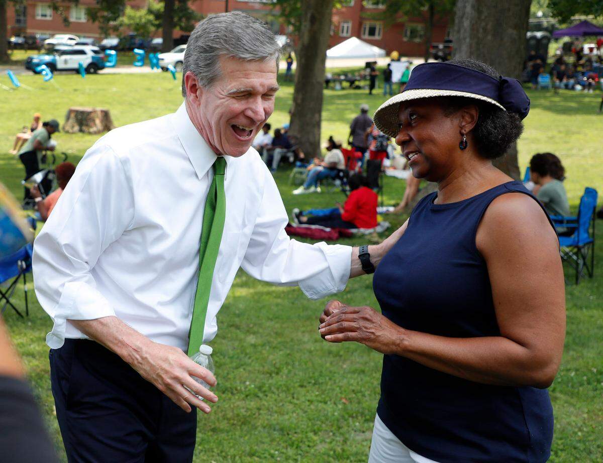 Gov. Roy Cooper laughs while talking with Carolyn Stroud of Cary during the Capital City Juneteenth Celebration 2021 at Dorothea Dix Park in Raleigh, N.C., Saturday, June 19, 2021.