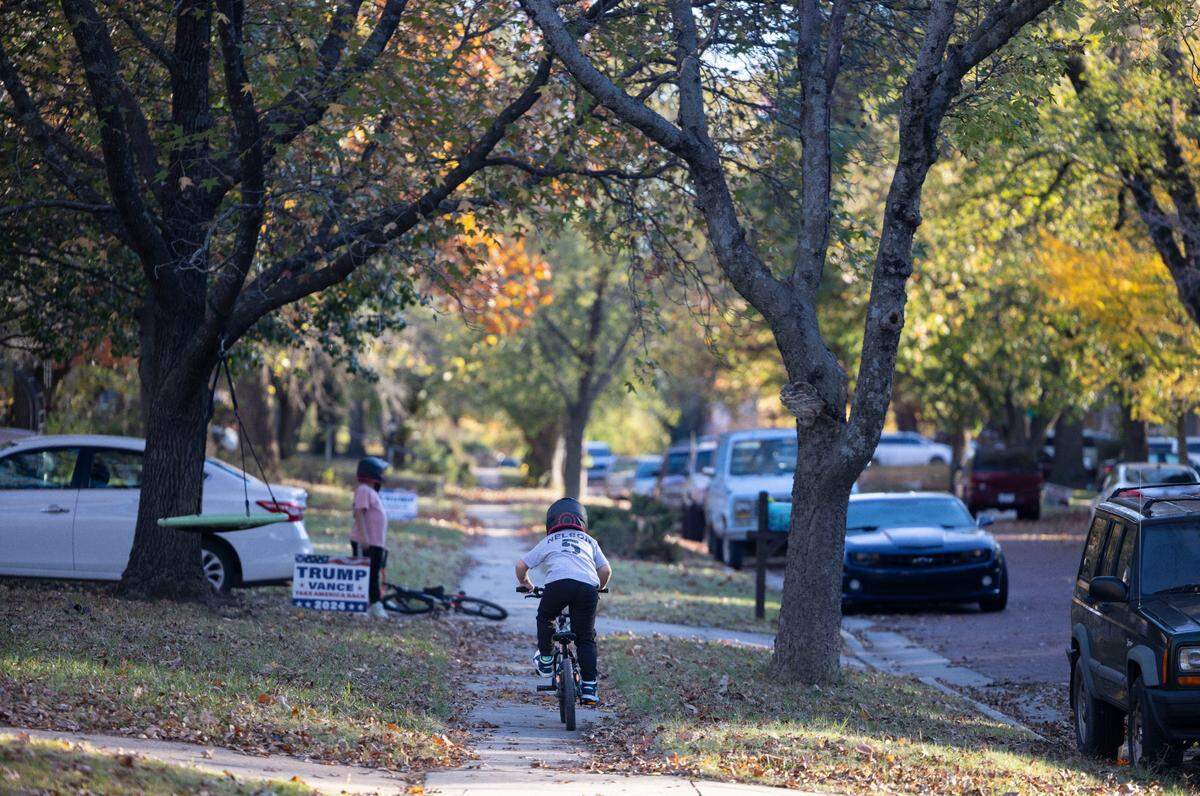 Children ride their bikes along tree lined Washington Street, in the neighborhood where North Carolina basketball coach Dean Smith grew up, on Wednesday, November 6, 2024 in Emporia, Kansas. 