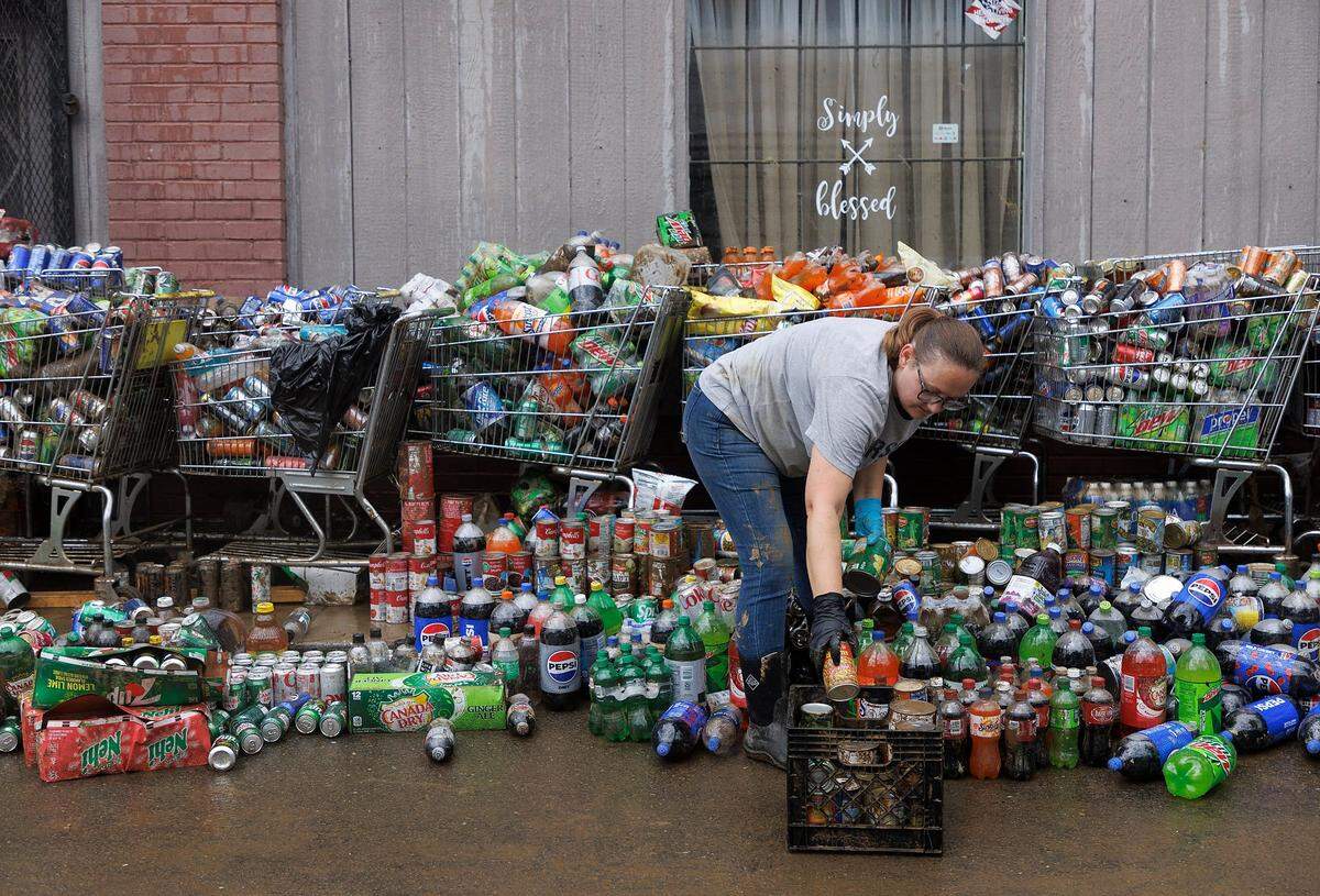 Hope Miller sorts canned goods to be donated to the food bank outside of CJ’s Market as community members clean up following damage from Hurricane Helene on Monday, Sept. 30, 2024, in Lansing, N.C.