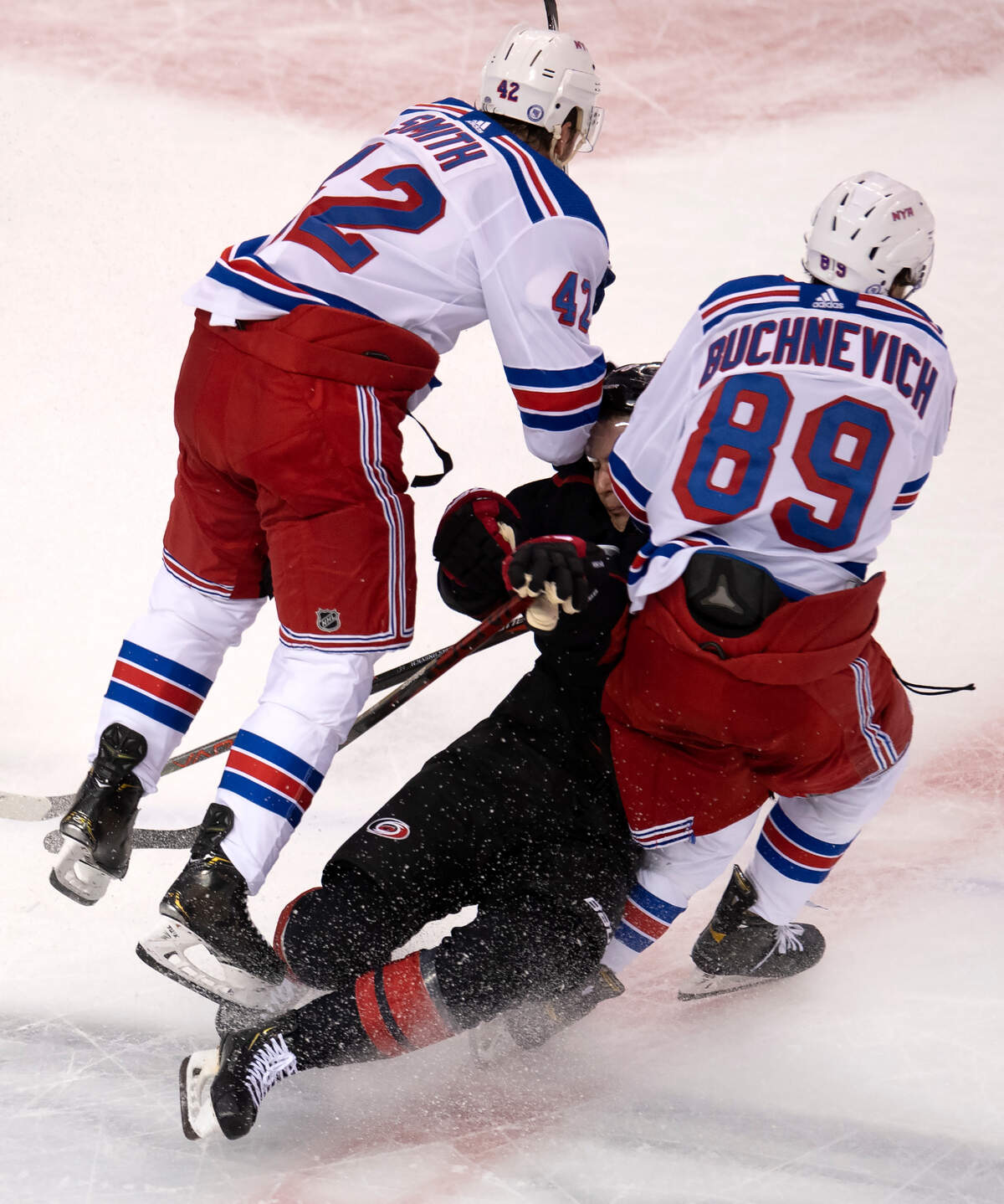 New York Rangers right wing Pavel Buchnevich (89) and defenseman Brendan Smith (42) knock Carolina Hurricanes center Martin Necas (88) to the ice during the first period in the NHL hockey Stanley Cup playoffs in Toronto, Saturday, Aug. 1, 2020. (Frank Gunn/The Canadian Press via AP)