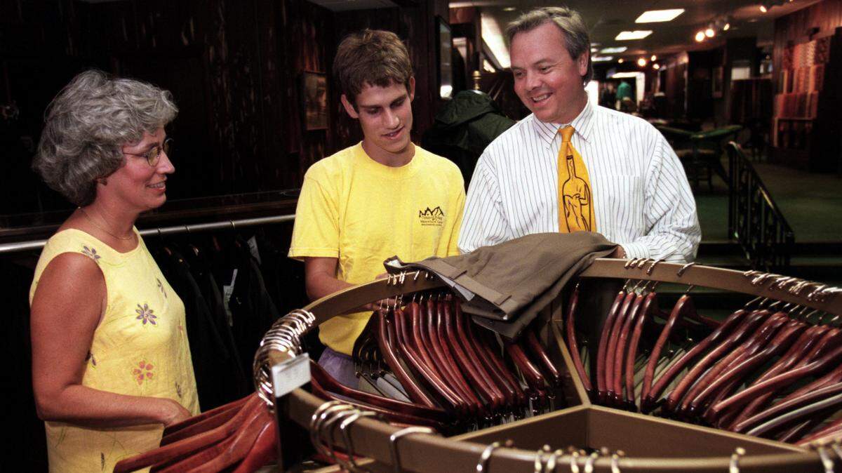 Salesman Barry Tharrington, right, helps customers Helen and Graham Roberts pick out a pair of pants at Nowell’s in Cameron Village in 1999.