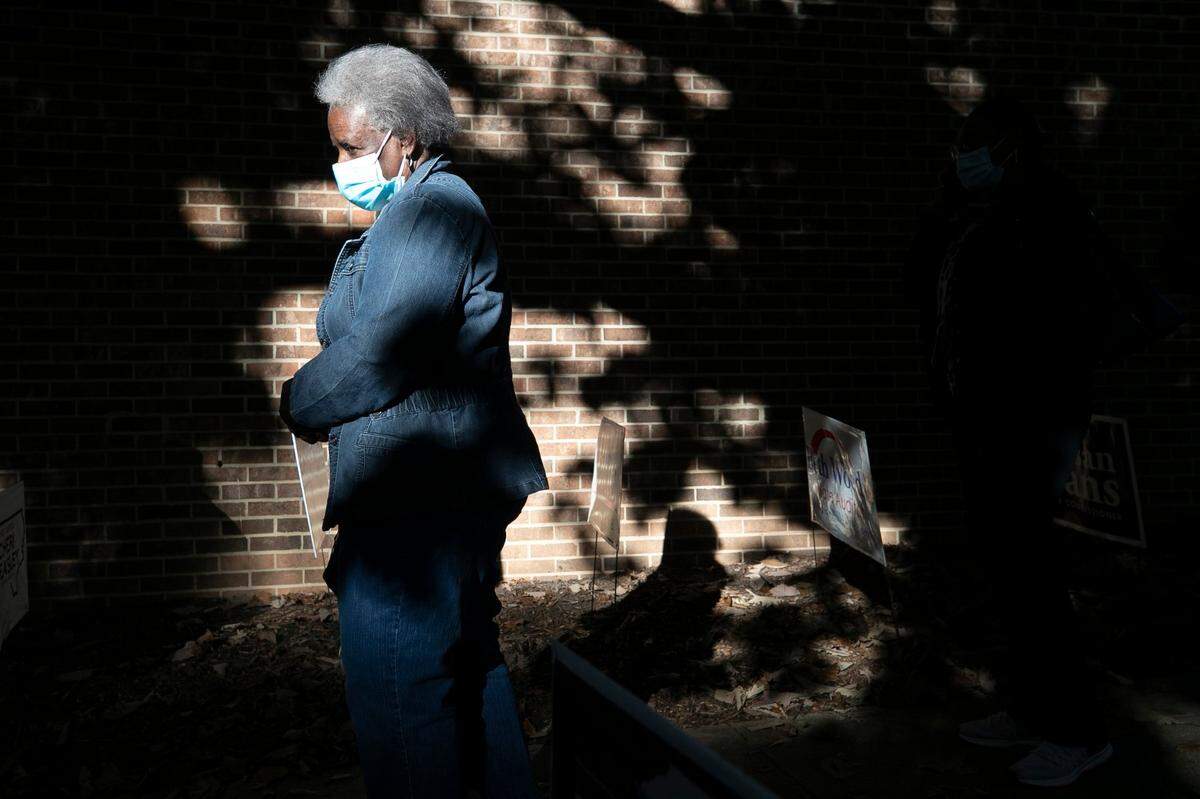The morning sun illuminates voters in line at Roberts Park on the first day of early voting in North Carolina on Thursday morning, October 15, 2020 in Raleigh, N.C.