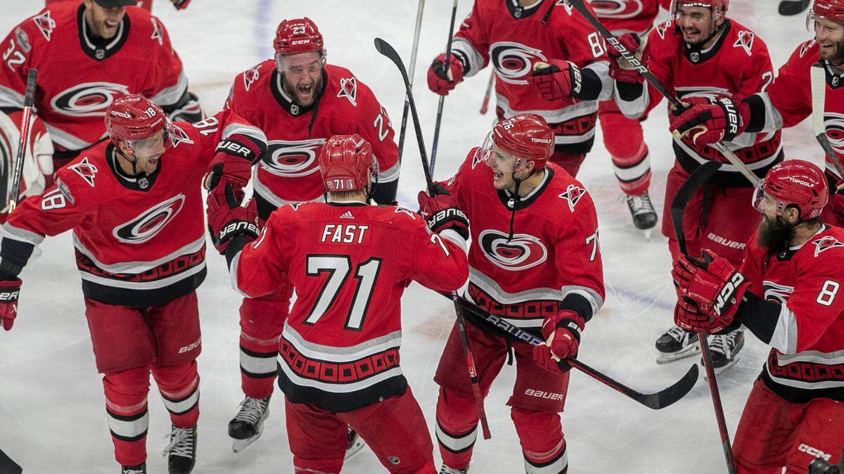 The Carolina Hurricanes swarm to Jesper Fast (71) during their post-game celebration after Fast scored the game winning goal in overtime to secure a 3-2 victory over the New Jersey Devils, clinching their second round Stanley Cup series on Thursday, May 11, 2023 at PNC Arena in Raleigh, N.C.