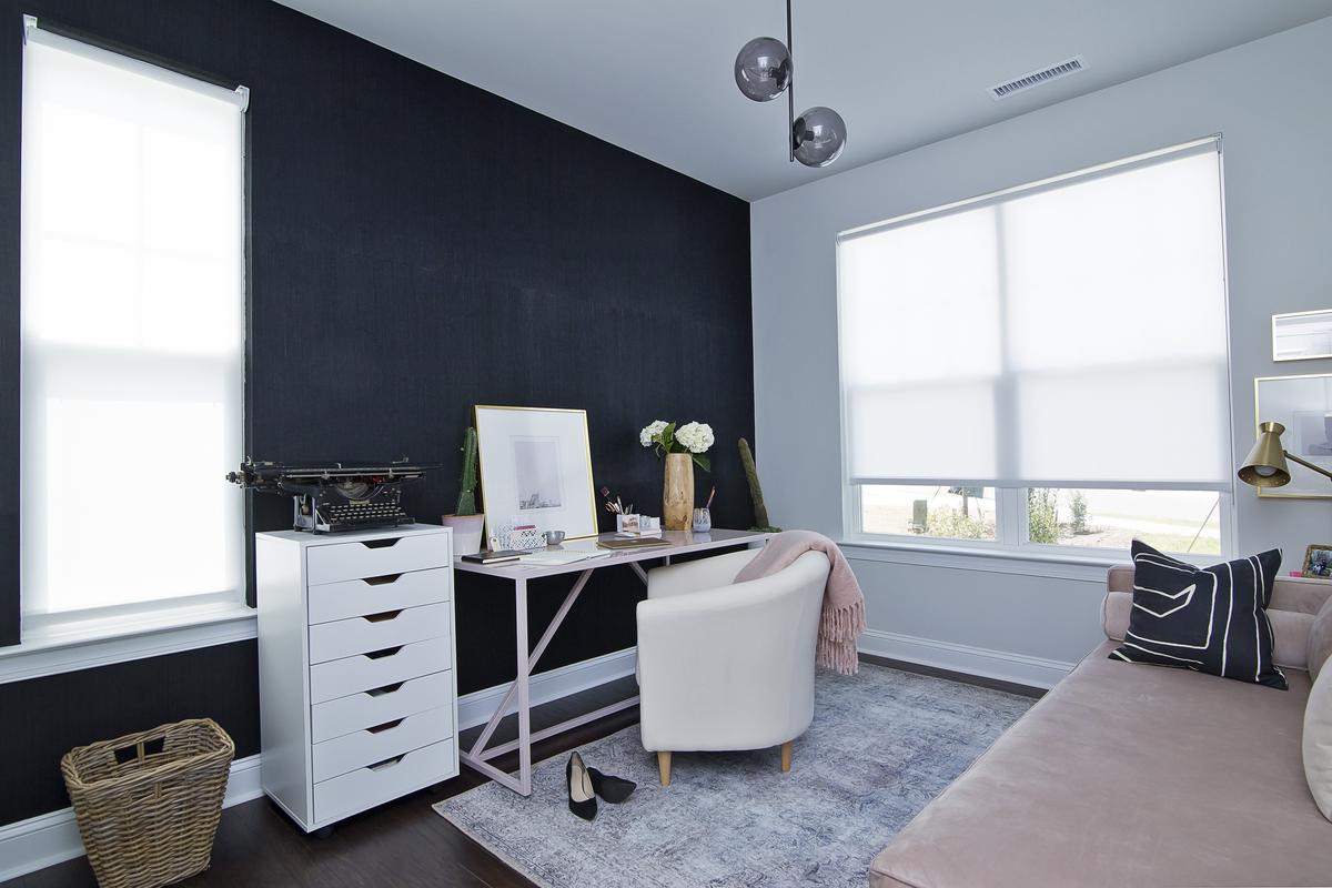 This office has a black grasscloth accent wall. Key items — the desk and mid-century couch — are pink. It’s a timeless color combination.
