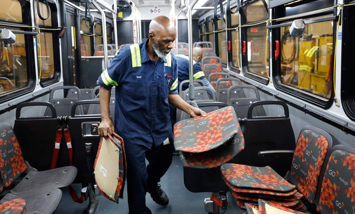 Daniel Moore piles up worn cloth seats while working on a GoRaleigh bus with Cody Lee at GoRaleigh’s maintenance headquarters off Poole Road on Saturday, May 10, 2025. Moore and Lee were taking out the old seat backs and bottoms and installing new vinyl ones.