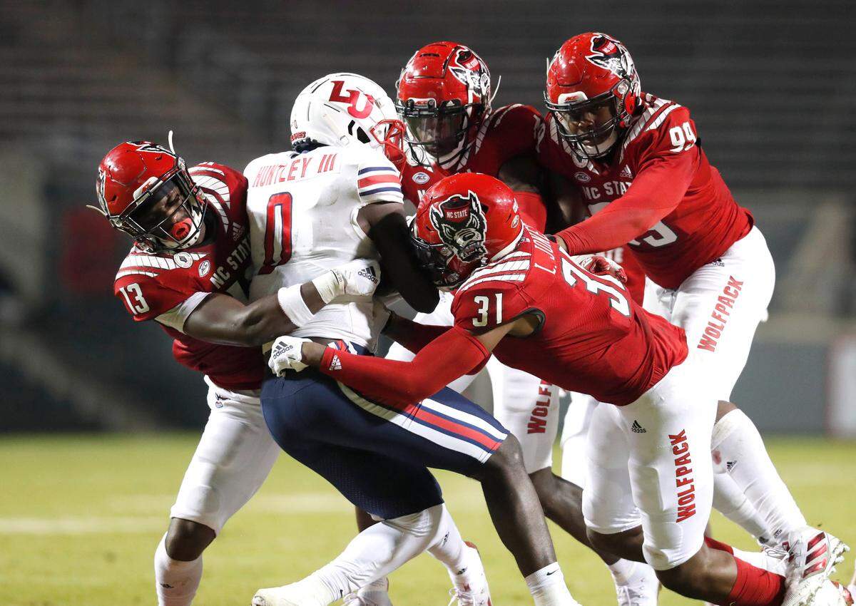 N.C. State’s Tyler Baker-Williams (13), Vi Jones (31), Cecil Powell (4) and Daniel Joseph (99) combine to tackle Liberty tight end Johnny Huntley (0) during the first half of N.C. State’s game against Liberty at Carter-Finley Stadium in Raleigh, N.C., Saturday, Nov. 21, 2020.