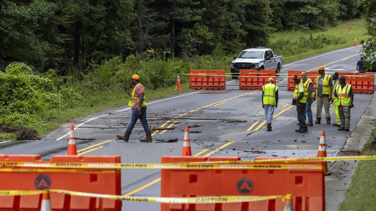 NCDOT workers assess damage to Olive Chapel Road in Apex after heavy rainfall caused Beaver Creek to wash out a section of the road on Wednesday, Aug. 6, 2025. The Apex Police Department announced via social media that the road will be closed for an “extensive length of time” until NCDOT can make repairs.