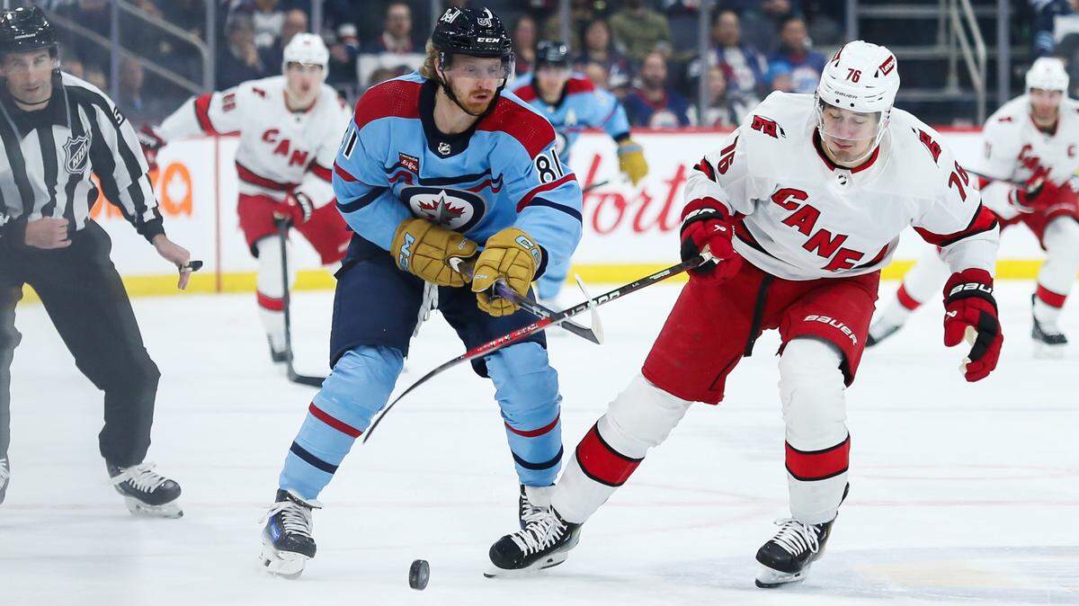 Dec 4, 2023; Winnipeg, Manitoba, CAN; Carolina Hurricanes defenseman Brady Skjei (76) and Winnipeg Jets forward Kyle Connor (81) go for the puck during the second period at Canada Life Centre. Mandatory Credit: Terrence Lee-USA TODAY Sports