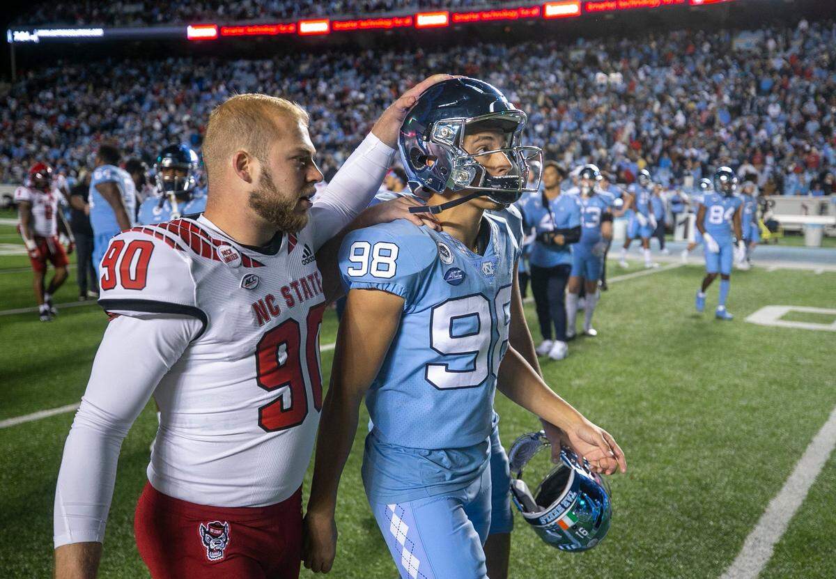 N.C. State kicker Collin Smith (90) consoles North Carolina kicker Noah Burnette (98) after Burnette missed a 35-yard field goal attempt in overtime to give N.C. State a 30-27 victory on Friday, November 25, 2022 at Kenan Stadium in Chapel Hill, N.C.