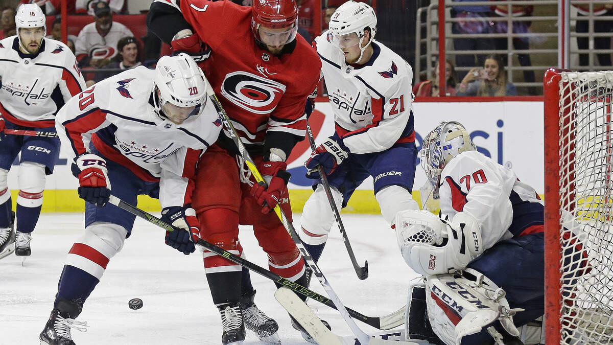 Carolina Hurricanes’ Phillip Di Giuseppe (7) tries to shoot on goal while Washington Capitals’ Lars Eller (20), of Denmark, Lucas Johansen (21) and goalie Braden Holtby (70) defend during the second period of a preseason NHL hockey game in Raleigh, N.C., Friday, Sept. 21, 2018.