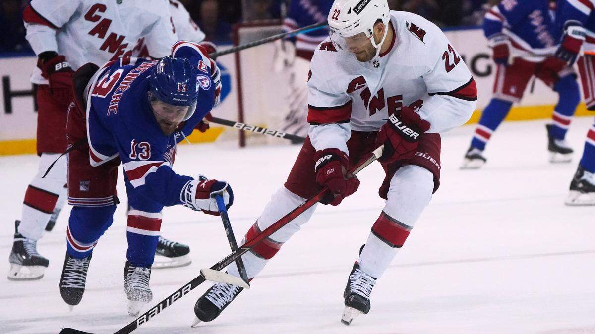 New York Rangers left wing Alexis Lafrenière (13) and Carolina Hurricanes defenseman Brett Pesce (22) vie for the puck during the second period of an NHL hockey game Tuesday, April 12, 2022, in New York. (AP Photo/Bebeto Matthews)