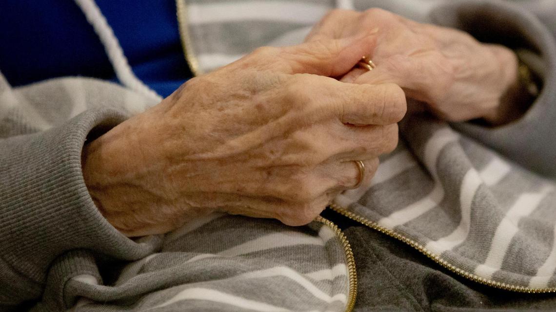 Thelma Miller clasps her hands while visiting with her daughters Cheryl Brown and Karen Espenhahn in the common area of a new home care house which Miller was one of the first of six residents to move into, with hopes of finding less isolation and more visitation freedom than traditional facilities can offer during the coronavirus pandemic, on Thursday, Dec. 17, 2020, in Cary, N.C.