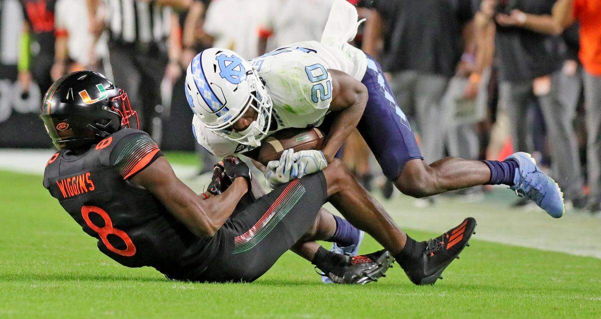 Miami Hurricanes wide receiver Xavier Restrepo (8) gets intercepted by North Carolina Tar Heels Tony Grimes (8) in the third quarter at Hard Rock Stadium In Miami Gardens, Florida, Saturday, December 12, 2020.