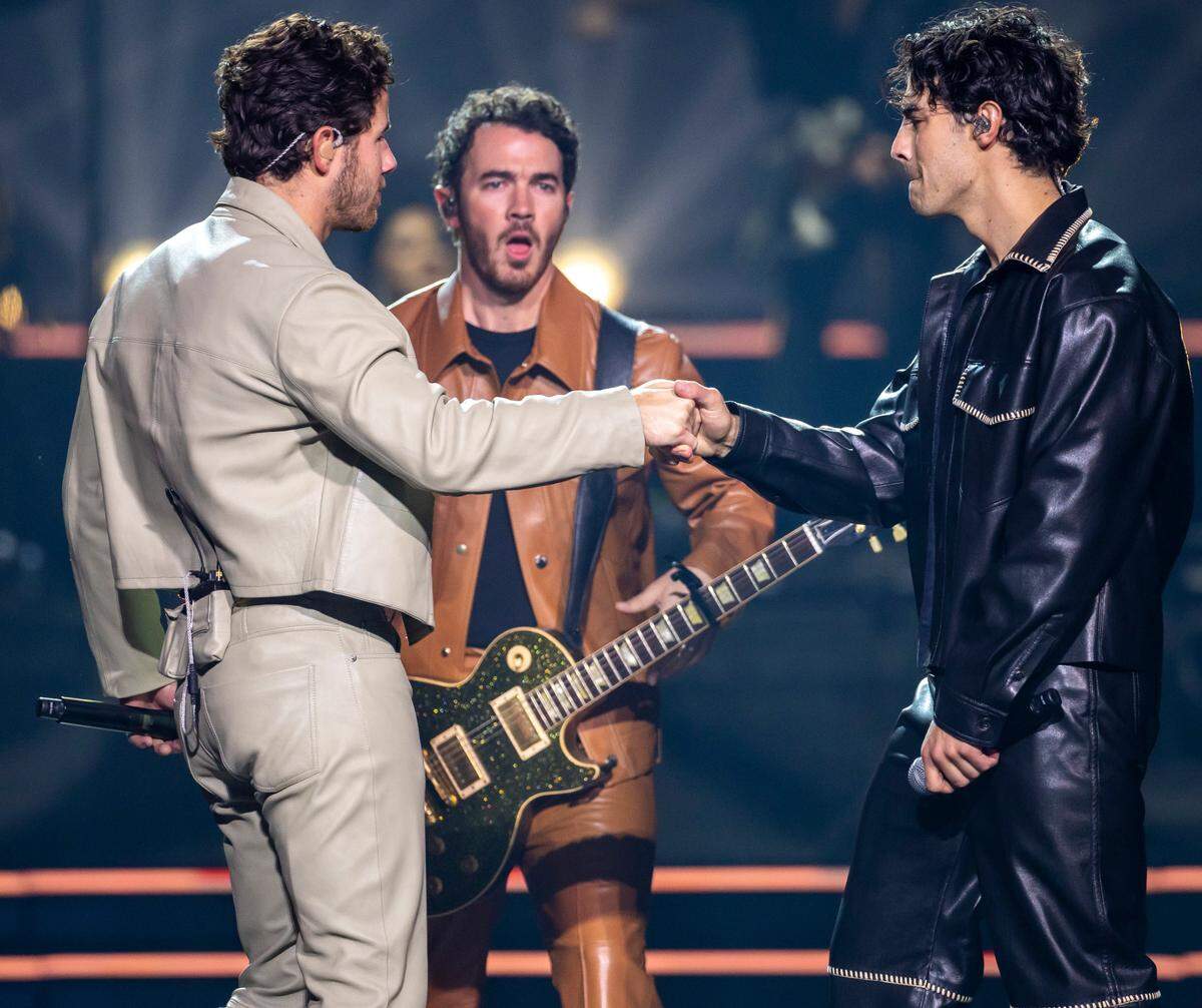 Nick and Joe Jonas greet each other as they take the stage with their brother Kevin during their “Five Albums, One Night” tour stop at the PNC Arena on Thursday, September 28, 2023 in Raleigh, N.C