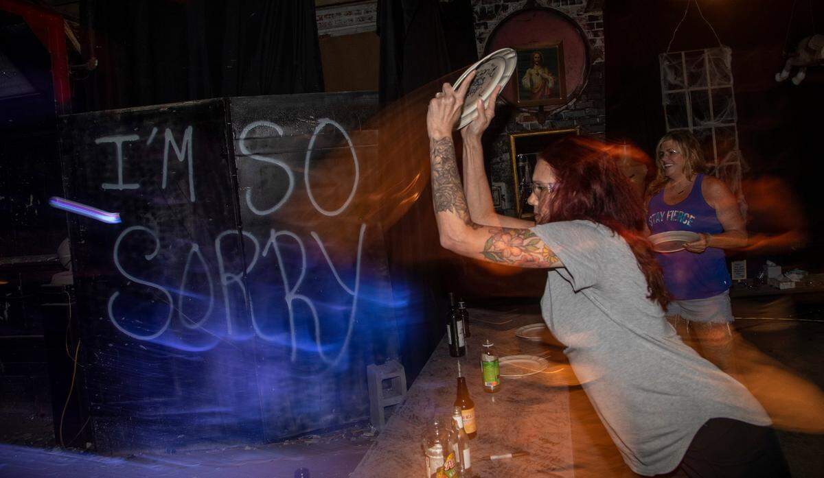Amy Wright , foreground, and Leila Ann Faries break glassware at Grievous Gallery rage and anger room in Salisbury.