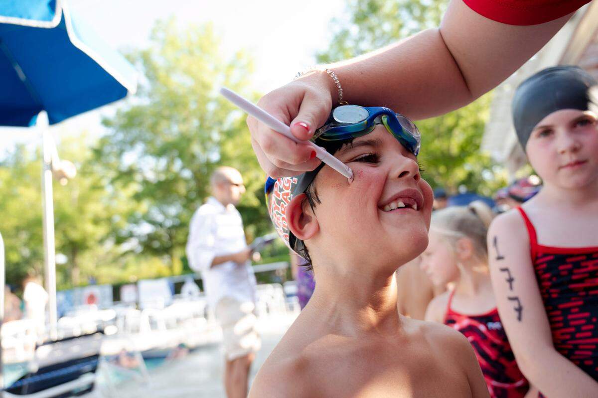 Harris Clare has his face painted by Coach Olivia Honaker during the Cary Park Swim Sea Dragons swim meet on June 25, 2024.