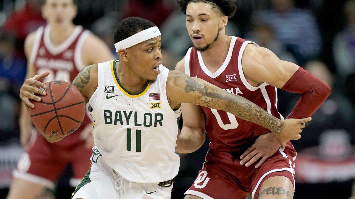 Baylor guard James Akinjo (11) drives past Oklahoma guard Jordan Goldwire (0) during the first half of an NCAA college basketball game in the quarterfinal round of the Big 12 Conference tournament in Kansas City, Mo., Thursday, March 10, 2022. (AP Photo/Charlie Riedel)
