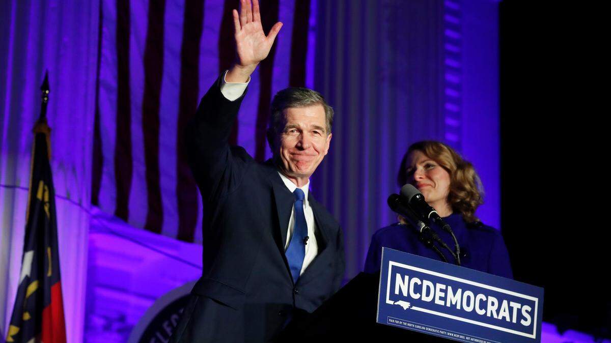 Gov. Roy Cooper waves after speaking outside the North Carolina Democratic Party headquarters in Raleigh in November 2020. Next to Cooper is his wife, Kristin Cooper.