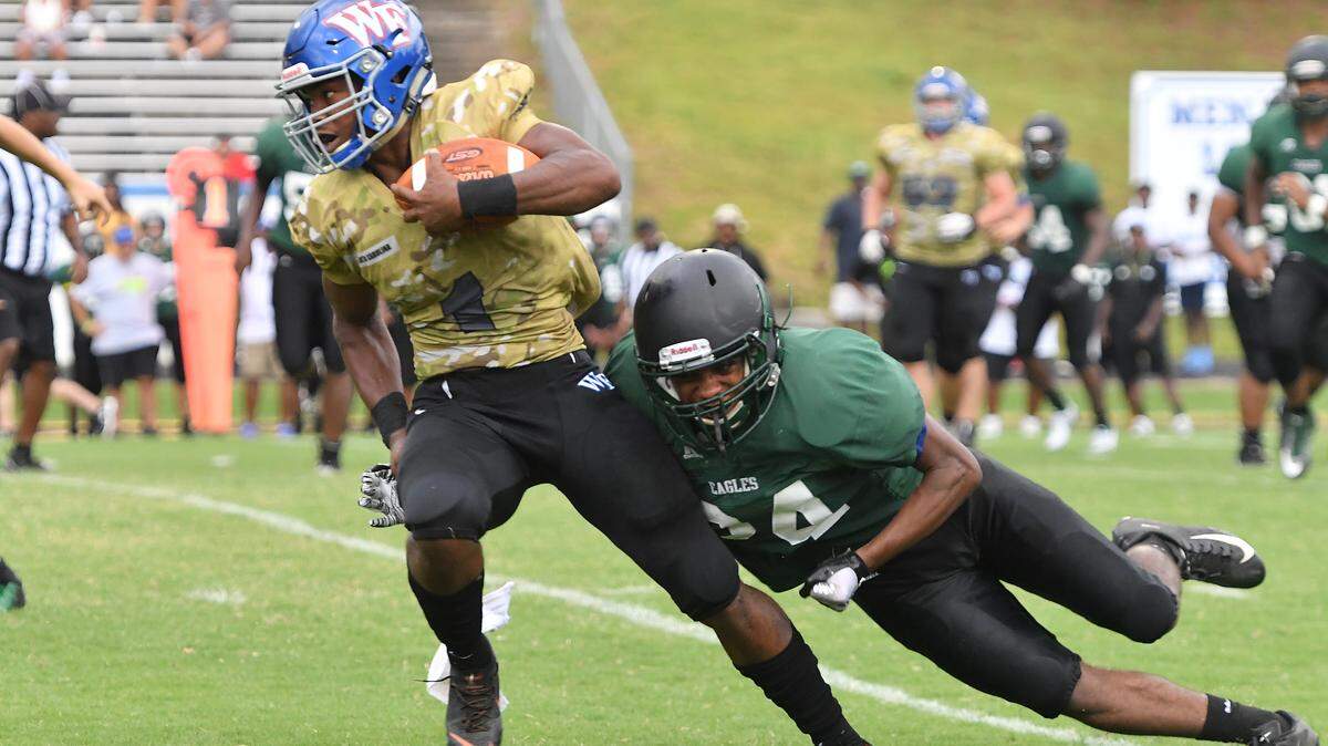 Kahlil Watson (1) of Wake Forest carries the ball against a tackle from Gregory Branch (24) of Enloe. The Wake Forest Cougars played the Enloe Eagles in a high school football scrimmage game on August 17, 2019.