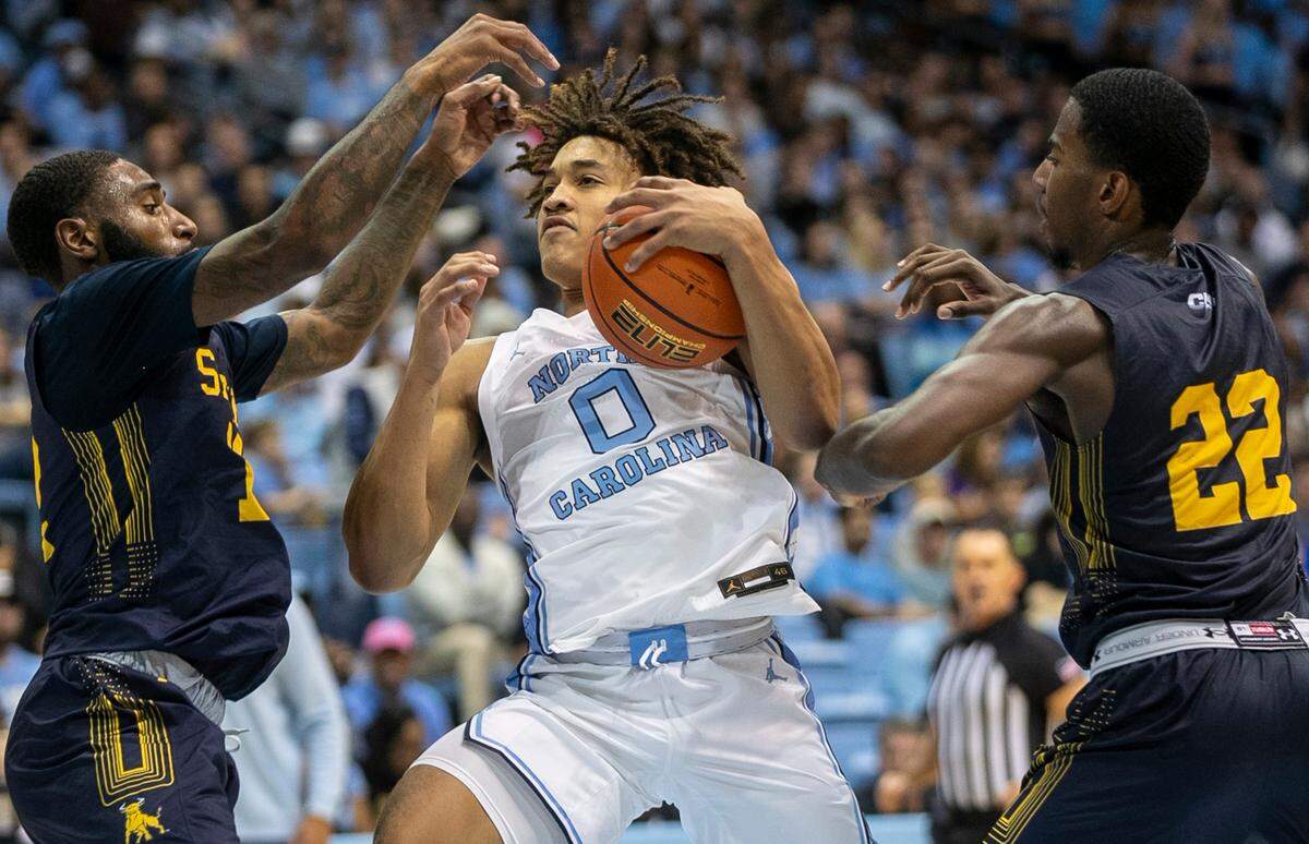 North Carolina’s Seth Trimble (0) drives to the basket between Johnson C. Smith’s Cartier Jernigan (12) and Javon Floyd (22) in the second half during an exhibition game on Friday, October 28, 2022 at the Smith Center in Chapel Hill, N.C.