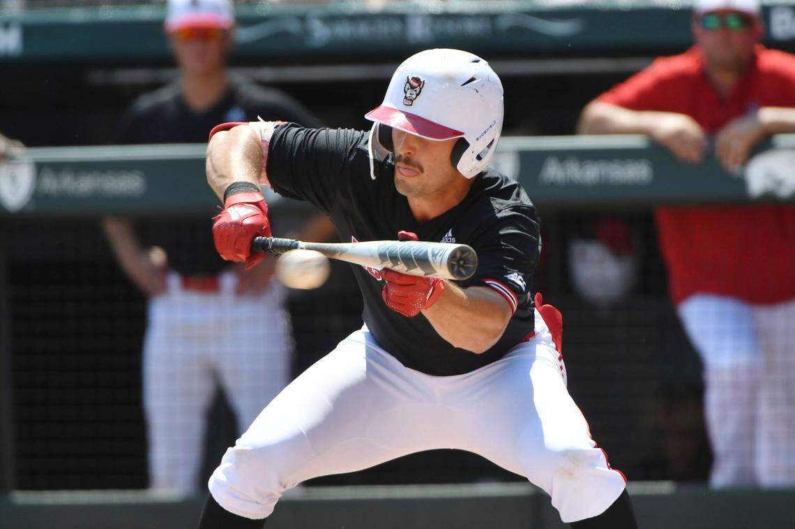 North Carolina State batter Austin Murr (12) lays down a bunt against Arkansas in the third inning of an NCAA college baseball super regional game Saturday, June 12, 2021, in Fayetteville, Ark. (AP Photo/Michael Woods)