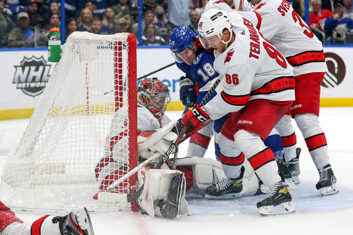 Tampa Bay Lightning’s Ondrej Palat (18) of Czech Republic, battles against Carolina Hurricanes’ Teuvo Teravainen (86), of Finland, for a puck under the pad of goaltender Frederik Andersen, of Denmark, during the second period of an NHL hockey game Tuesday, Nov. 9, 2021, in Tampa, Fla. (AP Photo/Mike Carlson)