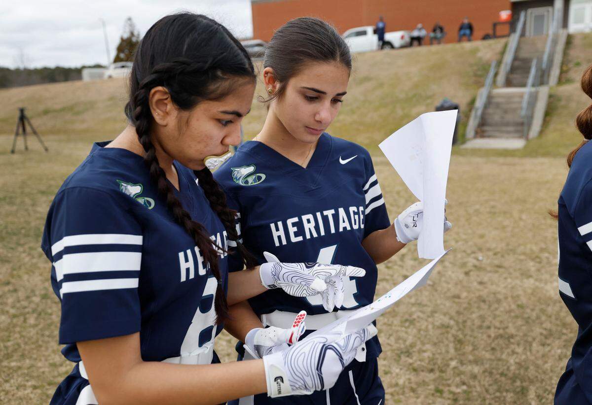 Heritage High School’s Maria Cardenas-Manzanilla, left, and Eva Correa look over plays during a flag football scrimmage at Heritage High School in Wake Forest, N.C., Wednesday, Jan. 24, 2024.