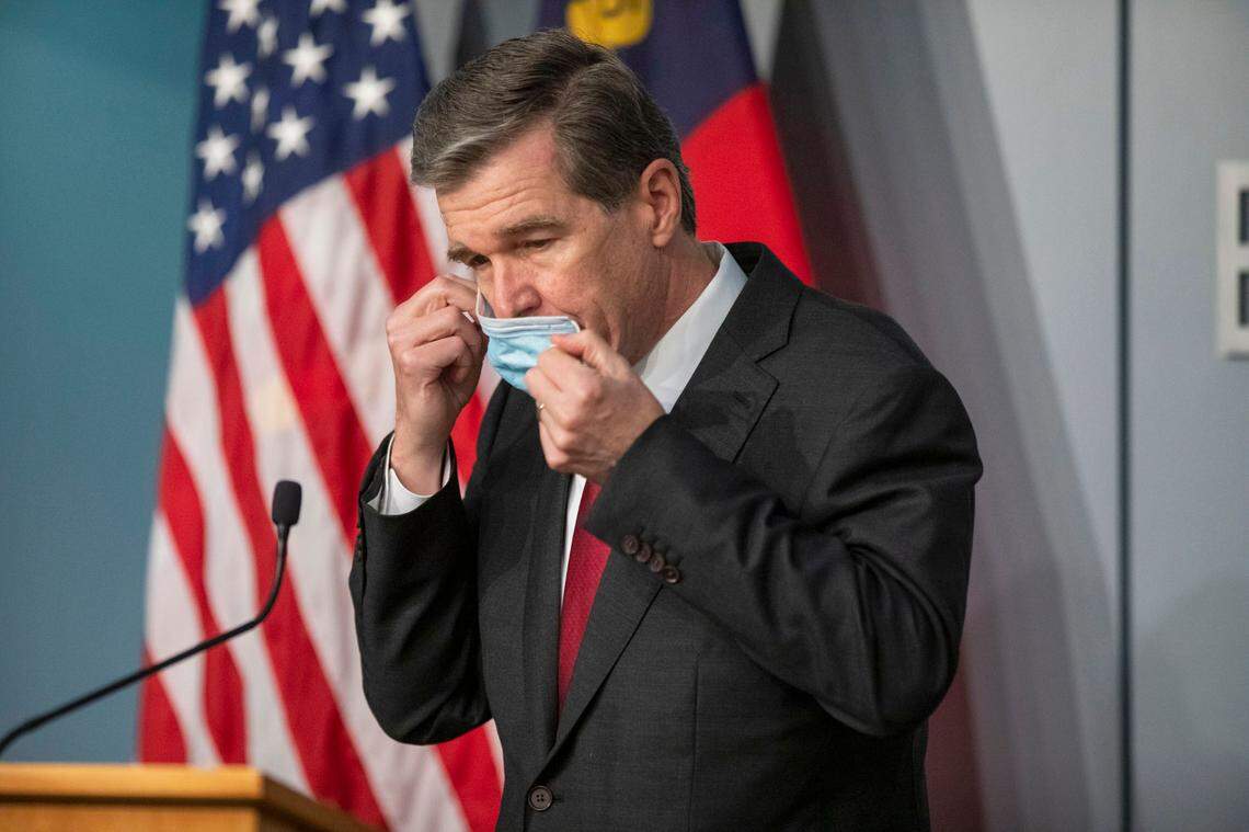 Gov. Roy Cooper removes his mask to begin a briefing earlier this month. This week, Cooper is expected to announce whether NC will enact a face mask mandate to slow the spread of COVID-19.