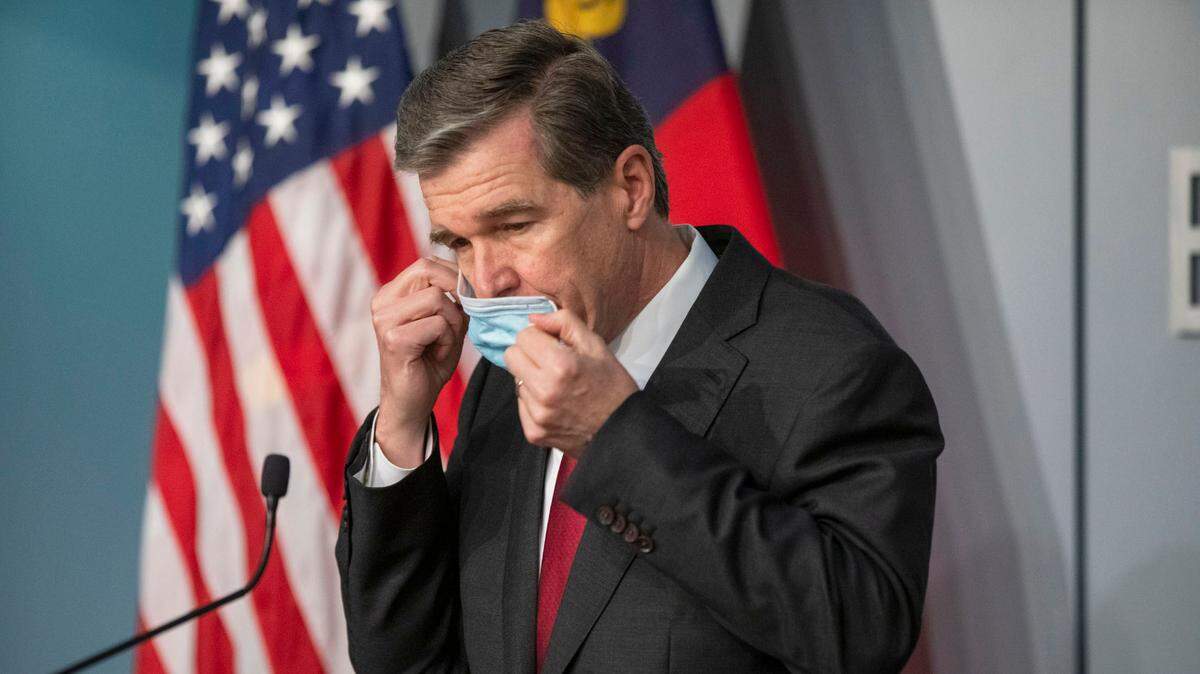 Gov. Roy Cooper removes his mask to begin a briefing earlier this month. This week, Cooper is expected to announce whether NC will enact a face mask mandate to slow the spread of COVID-19.