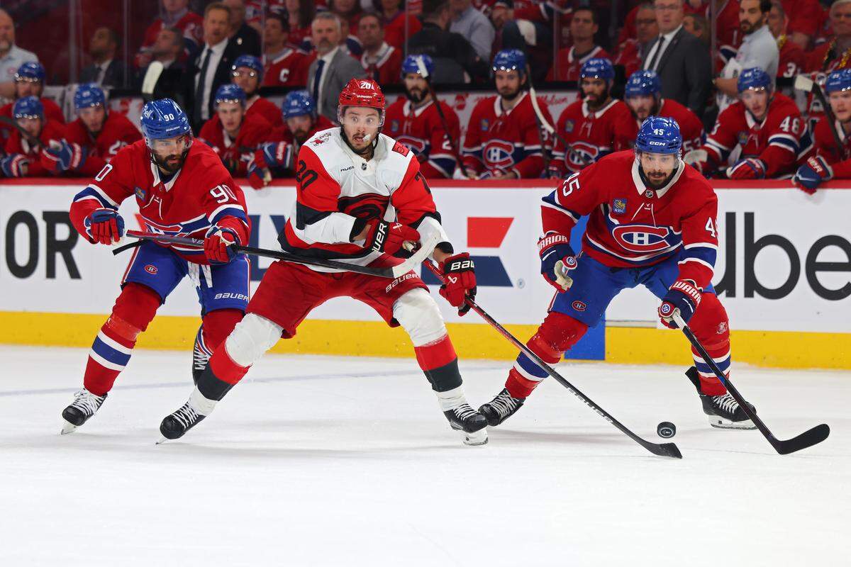 Sebastian Aho, center, of the Carolina Hurricanes controls the puck in front of Joe Veleno, left, and Alexandre Carrier of the Montreal Canadiens during the first period in Game 4 of the Eastern Conference Final of the 2026 Stanley Cup Playoffs at Bell Centre on May 27, 2026 in Montreal, Quebec, Canada.