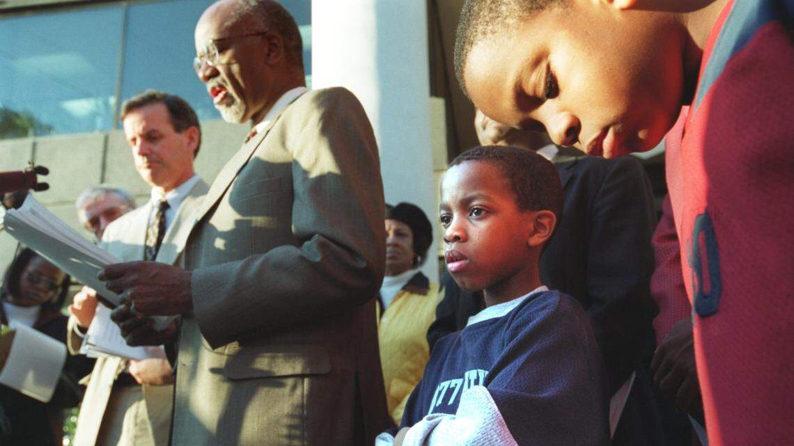Attorney James Feguson addresses the media about a court ruling affecting how race is used in determining student enrollment in Charlotte-Mecklenburg Schools. Students Omaria Collins, 7, and Salim Collins, 8, look on. The youngsters are sons of Dwayne Collins, one of the plaintiffs in the case. File photo Nov. 30, 2000