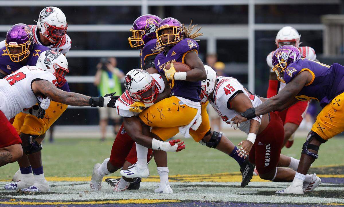 N.C. State linebacker Isaiah Moore (1) and defensive tackle Davin Vann (45) stop East Carolina running back Rahjai Harris (47) for no gain during the first half of N.C. State’s game against ECU at Dowdy-Ficklen Stadium in Greenville, N.C., Saturday, Sept. 3, 2022.