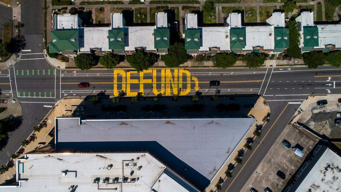 The word ‘defund’ is painted on Main Street in front of the Durham Police Headquarters building.