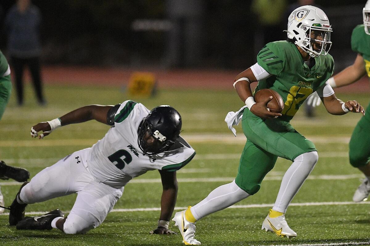 Cardinal Gibbons quarterback Gannon Jones (12) runs for yardage ahead of Leesville Road’s Xavier Lewis (6) in the second half. The Cardinal Gibbons Crusaders and the Leesville Road Pride met in a conference football game in Raleigh, N.C. on October 27, 2023.