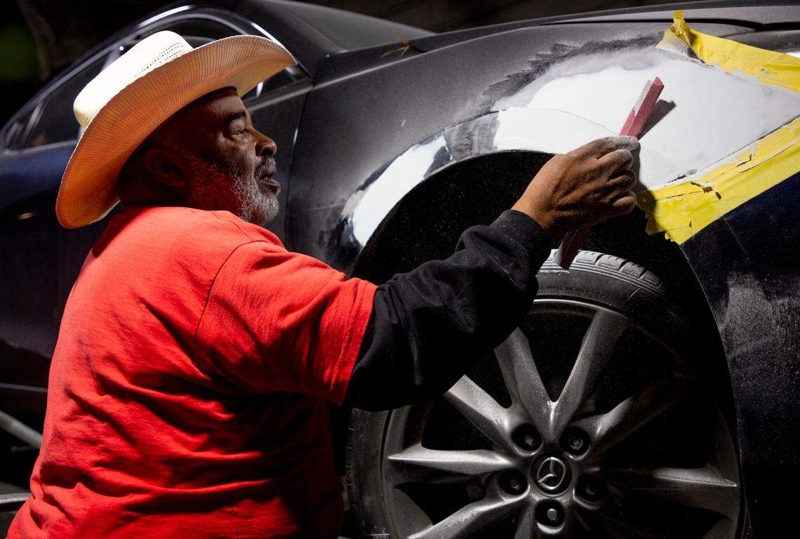 Brother Peacemaker, owner of Gates of Beauty Body Shop, sands a repair on the fender of a car in his shop, on Wednesday, Feb. 10, 2021, in Carrboro, N.C.
