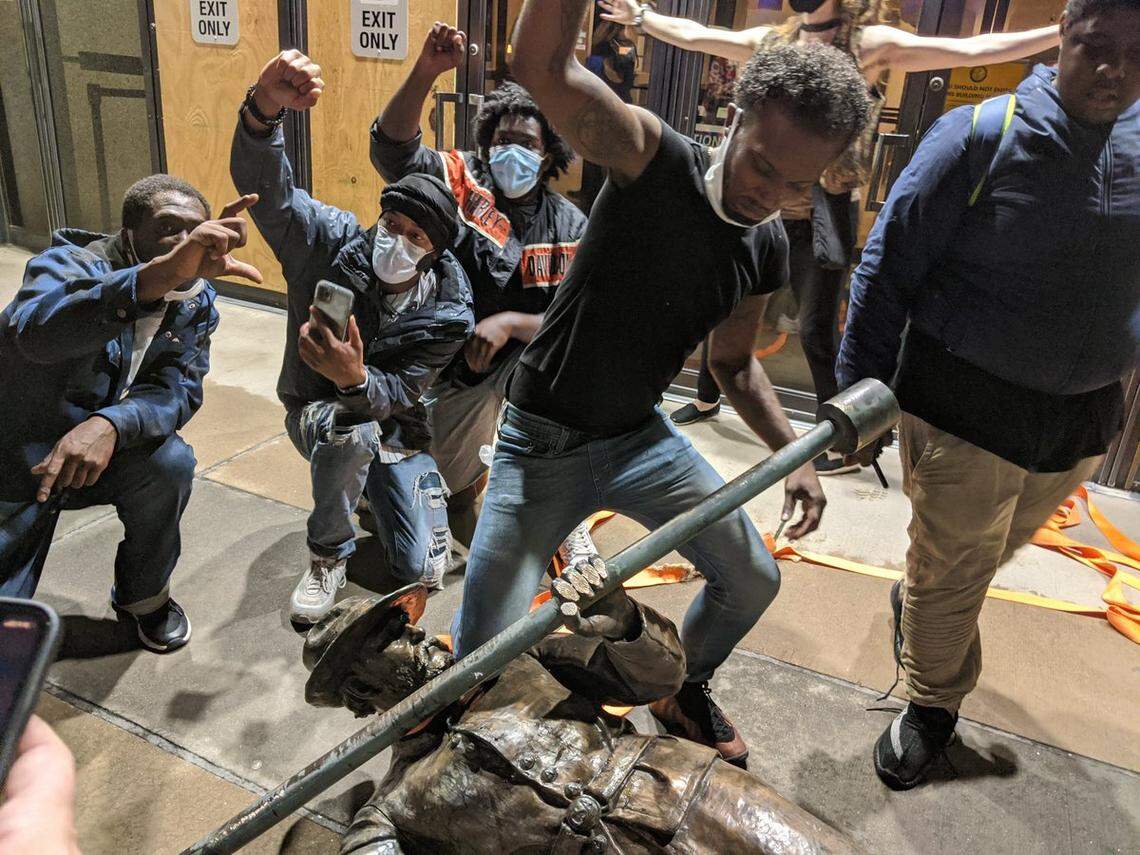 Protesters celebrate with one of the confederate statues pulled down from the N.C. State Capitol grounds Friday night, June 19, 2020.