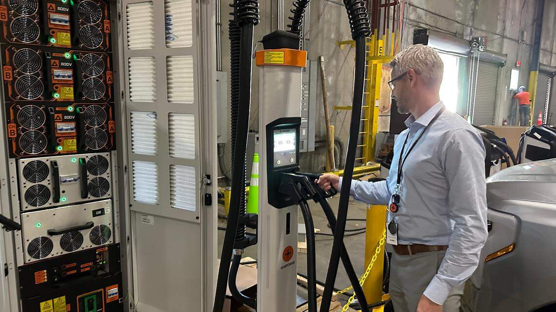 Marcus Suvanto of Kempower places a nozzle back in one of its EV charger satellites at the company’s new plant in Durham. The system’s power unit, left, can be placed up to 260 feet away from the satellites.