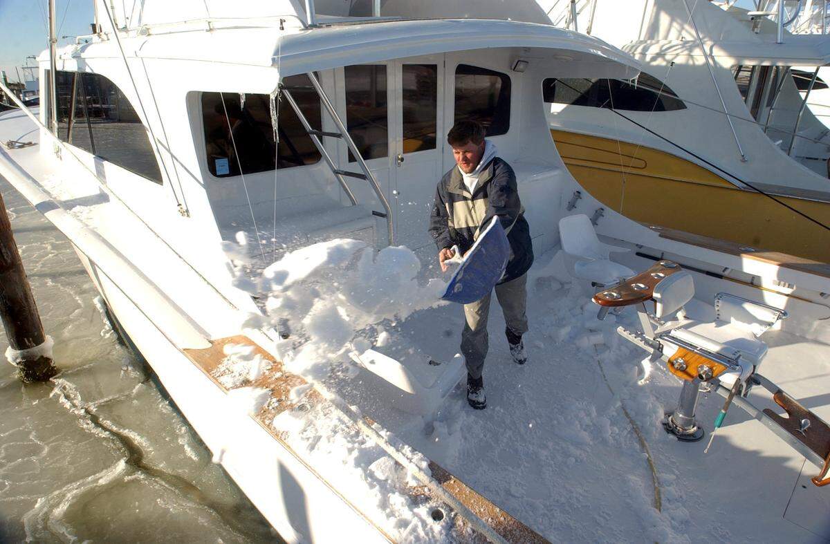 Kenneth Brown of Manteo, shovels snow from his boat the “Trophy Hunter” at the Oregon Inlet fishing center after a snow storm in January 2003. “I’ve never had to shovel my boat, it’s something we don’t get to do too often here”, Brown said as he dumped snow over into the frozen harbor.