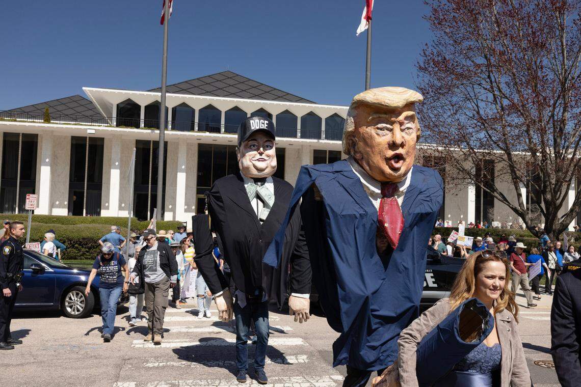 Large puppets of President Donald Trump and Elon Musk make their way across the street from the N.C. Legislative Building on Wednesday, March 12, 2025, following a protest in opposition to cuts and actions by DOGE and Elon Musk.