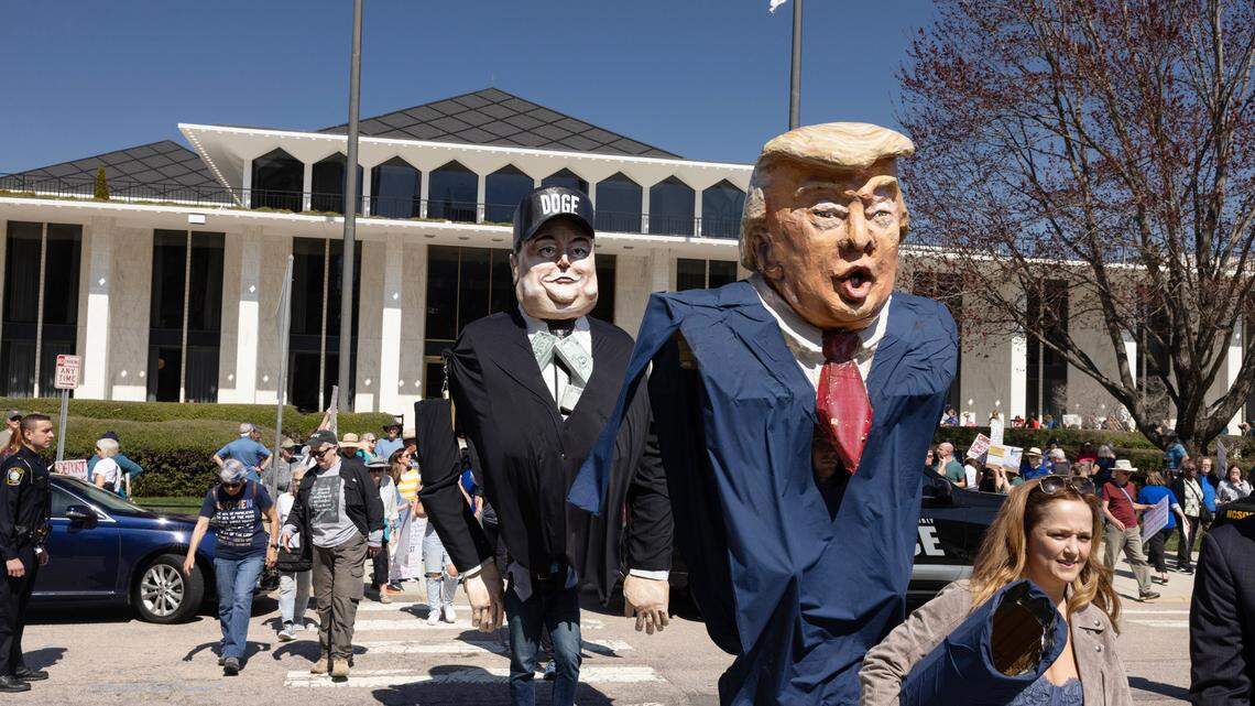 Large puppets of President Donald Trump and Elon Musk make their way across the street from the N.C. Legislature, Wednesday, March 12, 2025, following a protest in opposition to cuts and actions by DOGE and Elon Musk. Wednesday, March 12, 2025.