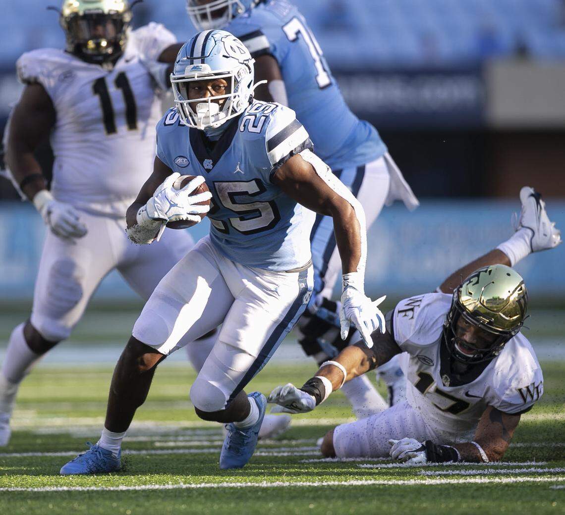 North Carolina’s Javonte Williams (25) scores on a 15-yard carry late in the fourth quarter, breaking away from Wake Forest’s Traveon Redd (17) to secure the Tar Heels’ 59-53 victory over Wake Forest at Kenan Stadium on Saturday, November 14, 2020 in Chapel Hill, N.C.