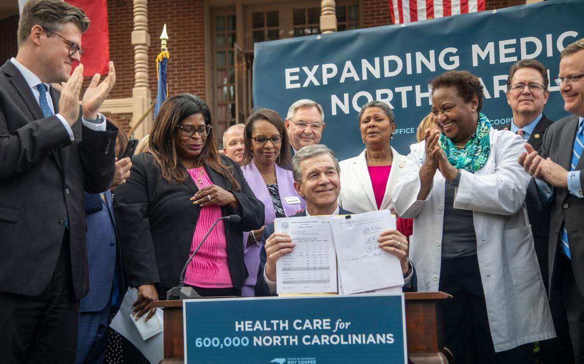 Gov. Roy Cooper holds up the Medicaid expansion bill after signing it into law during a ceremony at the Executive Mansion Monday, March 27, 2023.