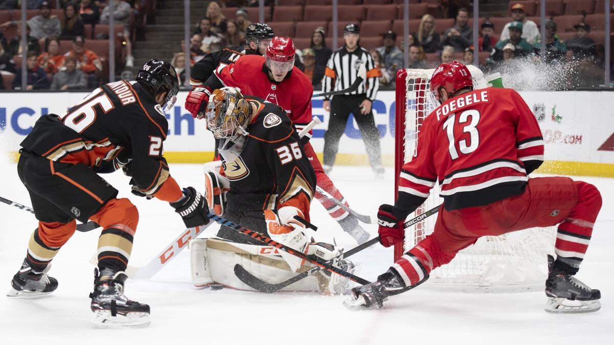 Anaheim Ducks goaltender John Gibson, center, blocks the shot by Carolina Hurricanes left wing Warren Foegele, right, during the first period of an NHL hockey game in Anaheim, Calif., Friday, Dec. 7, 2018. (AP Photo/Kyusung Gong)