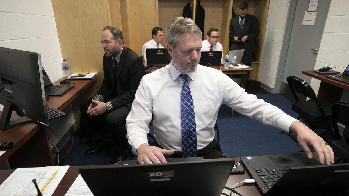 Carolina Hurricanes’ video coach Chris Huffine sets up two laptops with video feeds to capture game action, as does fellow video coach L.J.Scarpace, left, prior to the Hurricanes’ game against the Washington Capitals on Saturday, April 20, 2018 at the Capital One Arena in Washington, D.C. In the back of the room head coach Rod Brind’Amour confers with assistant coach Dean Chynoweth and goaltending coach Mike Bales while the players participate in pre-game skate.
