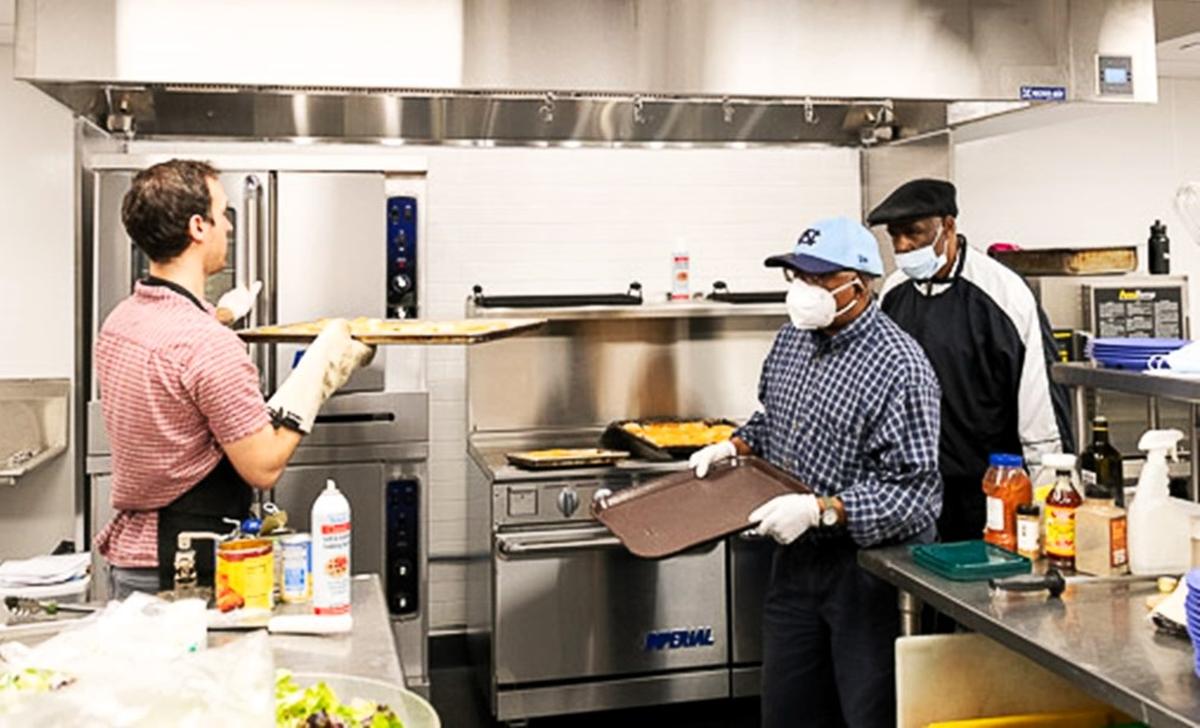 Club Nova members help prepare a meal for their colleagues in the new commercial kitchen at 103 W. Main St. in Carrboro. Pizza Friday is the most popular day of the week, according to Club Nova chef Andrii Bodnarchuk.
